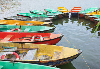 Obraz premium Aged polyester multi colored row boats moored in a lake.