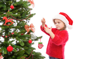Little girl hanging Christmas decoration on the tree