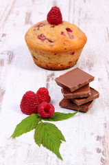 Fresh baked muffins with raspberries and chocolate on wooden background, delicious dessert