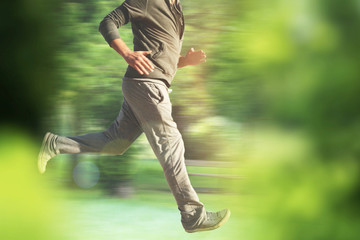 running man in park - partial image of man, with healthy lifestyle, doing physical activity jogging in park, wearing casual sportswear - blurry view from behind bushes with heavy motion blur