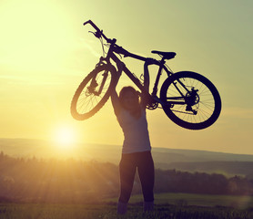 Obraz premium Girl with bicycle in the sunset