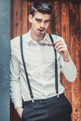 Young stylish man model posing near the wood wall. Fashion shot
