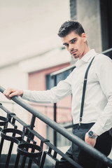 Young stylish man model in classic clothes posing near stairs. Fashion shot