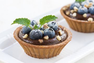 chocolate mousse with blueberries, nuts and mint in tartlets