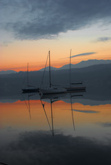 le barche riflesse sull'acqua del lago ,alla luce del tramonto