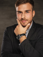 A man in a black suit over grey background.