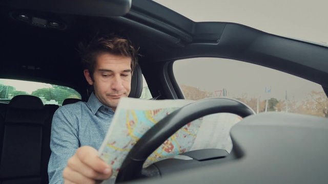 Lost man looking at a map with difficulty in car