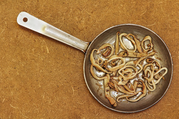 Roasted squids piecesin frying pan on wooden background.Top view