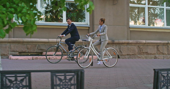 Tracking shot of white collar workers riding to office on bicycles 