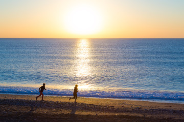 Fototapeta premium Sporty Couple doing Morning Jogging on Sea Beach at Sunrise