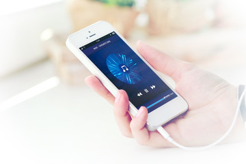 Music smartphone in female hand, on light background