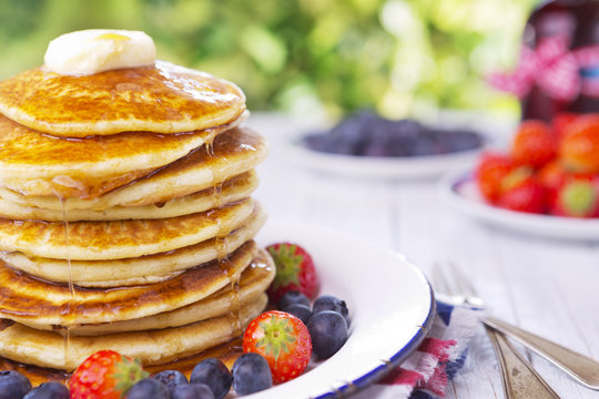 Stack of pancakes with fresh fruit, syrup and butter