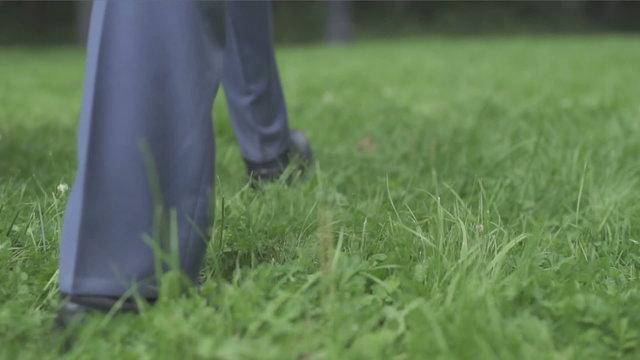 man in black shoes walking on the lawn
