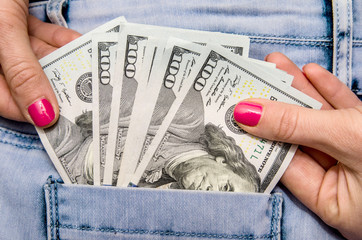 hand of woman pulling dollar money bill in pocket jeans