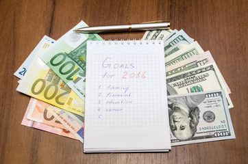 resolutions for new year 2016 with dollar and euro on wooden table