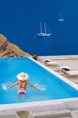 Woman in the swimming pool against open sea on Santorini island in Greece