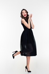 Attractive excited young woman with retro hairstyle in black dress