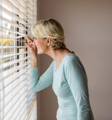senior woman peeking through the blinds