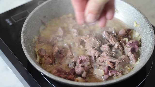 putting salt on fried livers with onion
