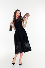 Attractive winking  woman holding bottle of champagne and gift