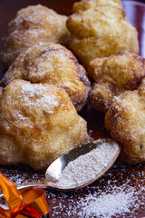 Spanische Buñuelos mit Zimtzucker und einem Desserlöffel mit Zimtzucker im Vordergrund