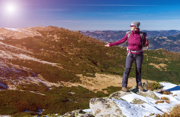 Female Hiker standing on snowy Rocks admiring scenic Winter Mountain View Sun