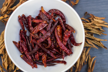Dried chili pepper in white bowl on dried Leaves and Wood background