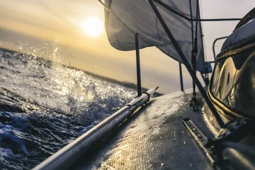 Abwaschbare Fototapete Segeln Segelboot fährt schnell bei Sonnenuntergang