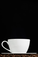 Cup of coffee and roasted beans over dark background