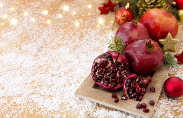 Fresh ripe pomegranates on wooden background and Christmas decoration.