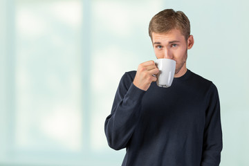 Young handsome man holding warm cup of tea/coffee