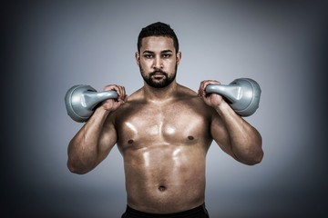 Fototapeta na wymiar Composite image of muscular man lifting heavy kettlebell 