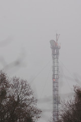 Relay tower with red lights in the fog