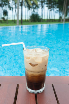 Iced coffee on the table beside the pool