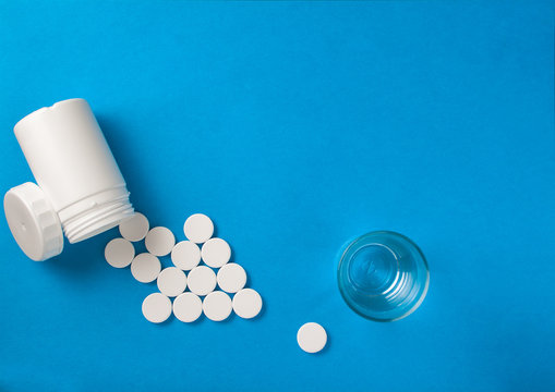 Effervescent pills coming from a white tube shaping an arrow on