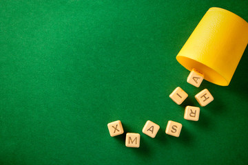 A set of character dices cast from a yellow cup expressing xmas