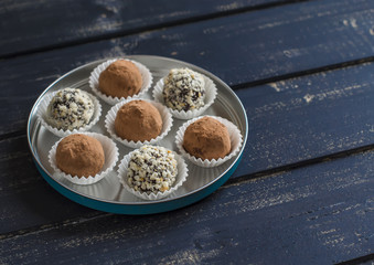 Assorted homemade candy - dark chocolate truffles with nuts and cocoa on dark wooden surface