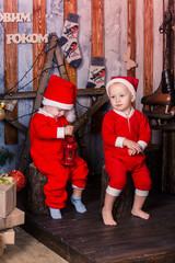 Happy little babys in Santa's costumes near Xmas tree