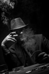 Male gambler playing poker, drinking whiskey and smokes a cigar, Black and white