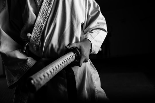 Close up of young martial arts fighter with katana siting in seiza position, black and white.