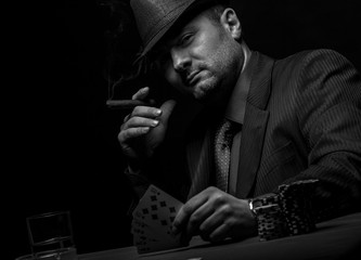 Male gambler playing poker, drinking whiskey and smokes a cigar, Black and white