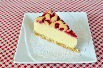cheesecake with raspberry sauce on white plate.