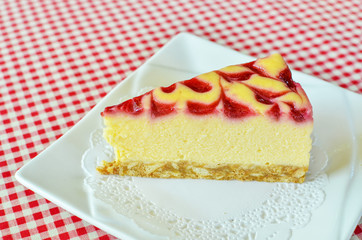 cheesecake with raspberry sauce on white plate.