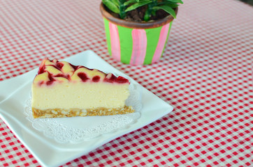 cheesecake with raspberry sauce on white plate.