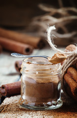 Ground cinnamon in a glass jar with a spoon, selective focus