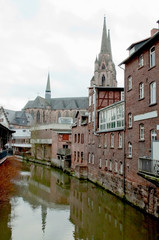 Fototapeta na wymiar Old brick houses and a church near the water channel in the historical center of Marburg, Germany