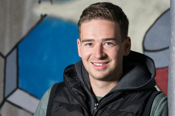 Smiling young Man in front of a Graffiti