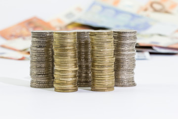 coins of 2 and 1 euros stacked and euro banknotes on a white background
