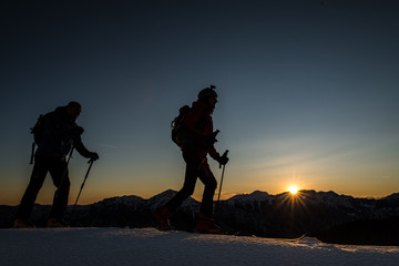 Ski mountaineers climb mountains with ski in the evening at suns