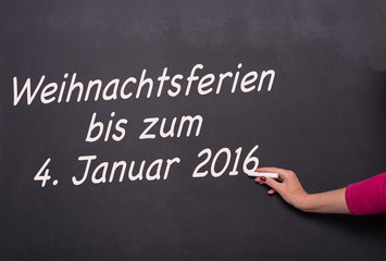 Fototapeta premium Frau schreibt an die Tafel Weihnachtsferien